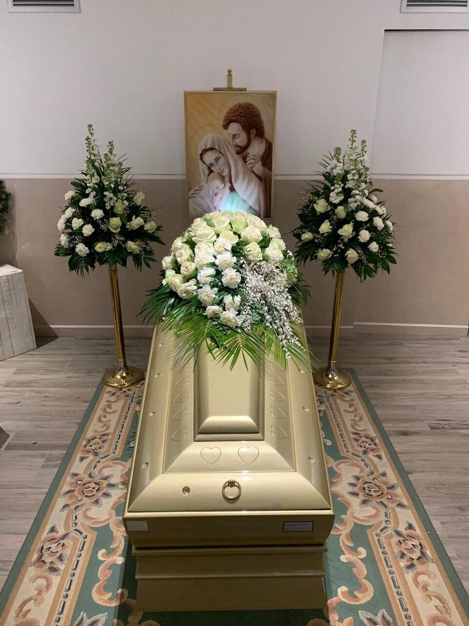 Ein geschlossener Sarg mit weißen Rosen in einem Abschiedsraum