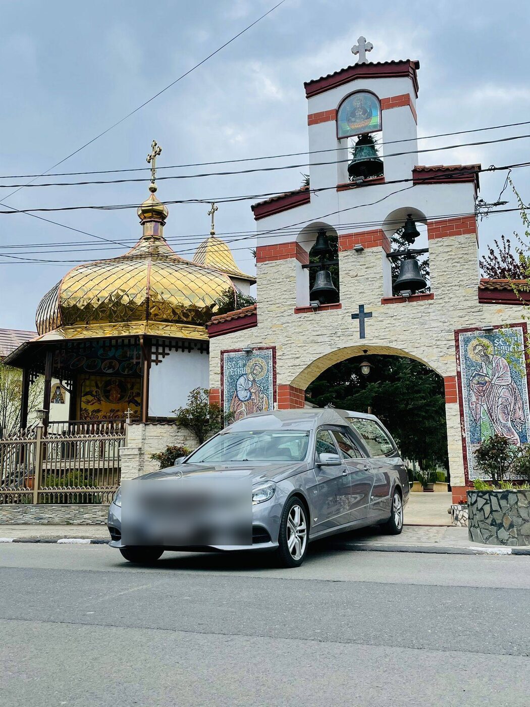 Silberner Mercedes-Bestattungswagen vor einer Kirche mit goldenen Kuppeln