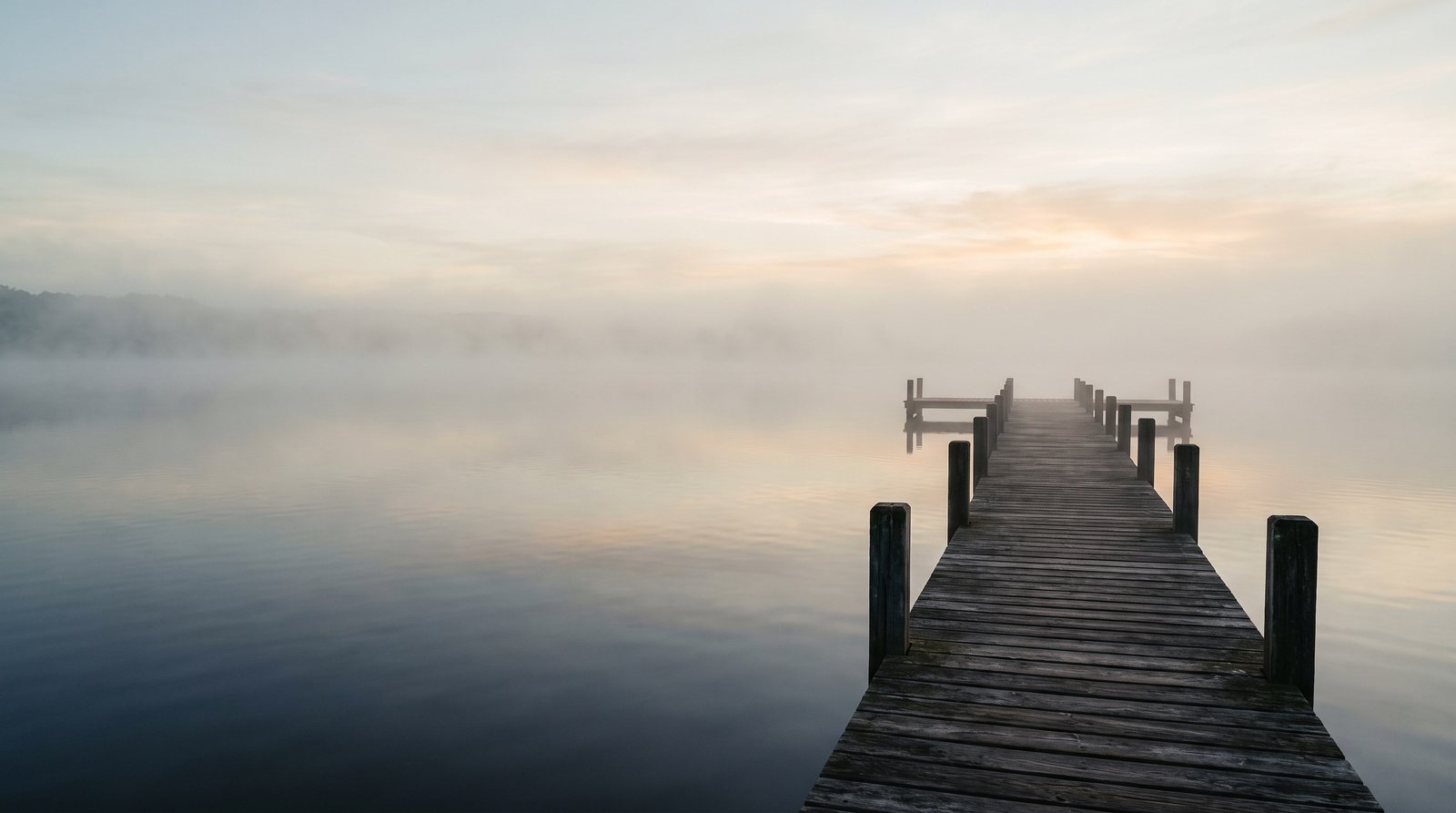 Holzsteg an einem See im Morgennebel