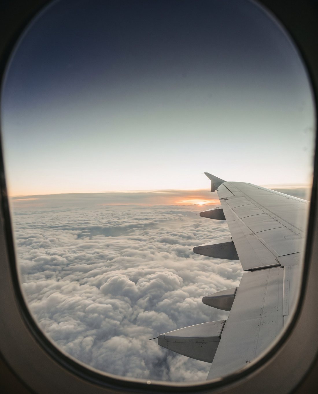 Wolken bei Sonnenaufgang durch ein Flugzeugfenster