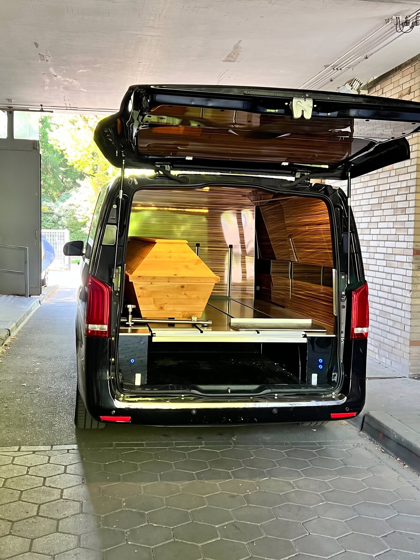 Transporter mit holzverkleidetem Innenraum und einem Kiefernsarg darin