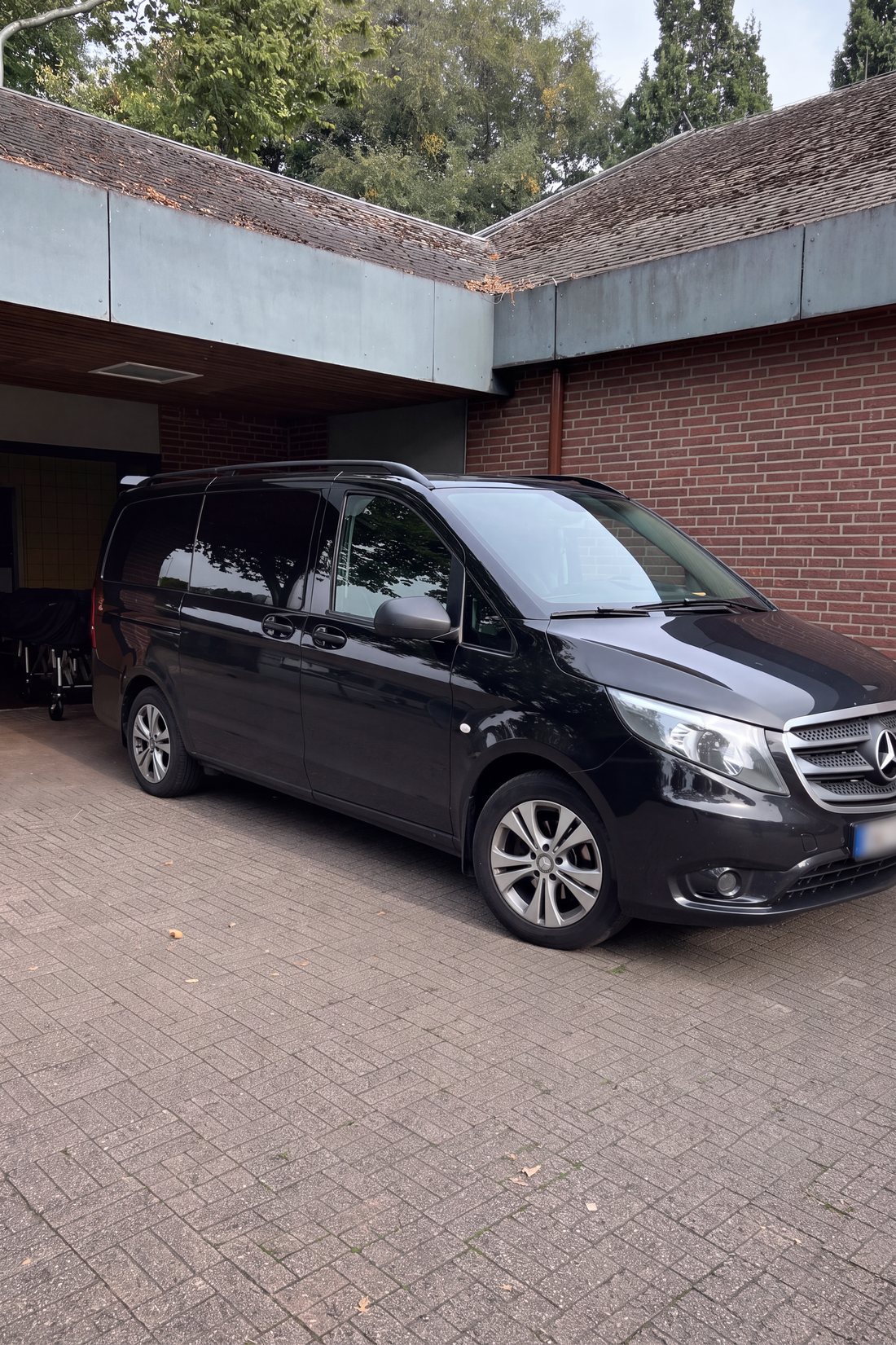 Schwarzer Mercedes-Transporter an einem Backsteingebäude mit Vordach