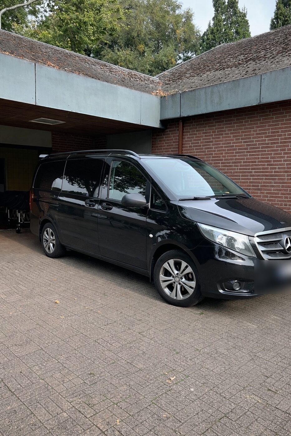 Black Mercedes van by a brick building with a canopy